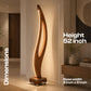 A tall sculptural floor lamp with a curved wooden body and warm LED lighting, shown in a modern interior setting with overlaid dimension labels reading 52 inch height and 8 inch by 6 inch base.